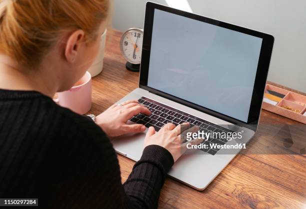 woman working on laptop at home office - clock person desk stockfoto's en -beelden