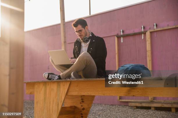 young man sitting on platform using laptop - using laptop outside stock pictures, royalty-free photos & images