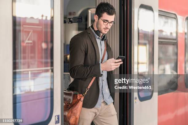 young man using cell phone in commuter train - commuter train stock pictures, royalty-free photos & images