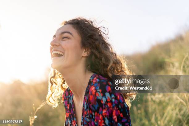 portrait of a young woman standing in meadow, laughing - só mulheres jovens imagens e fotografias de stock