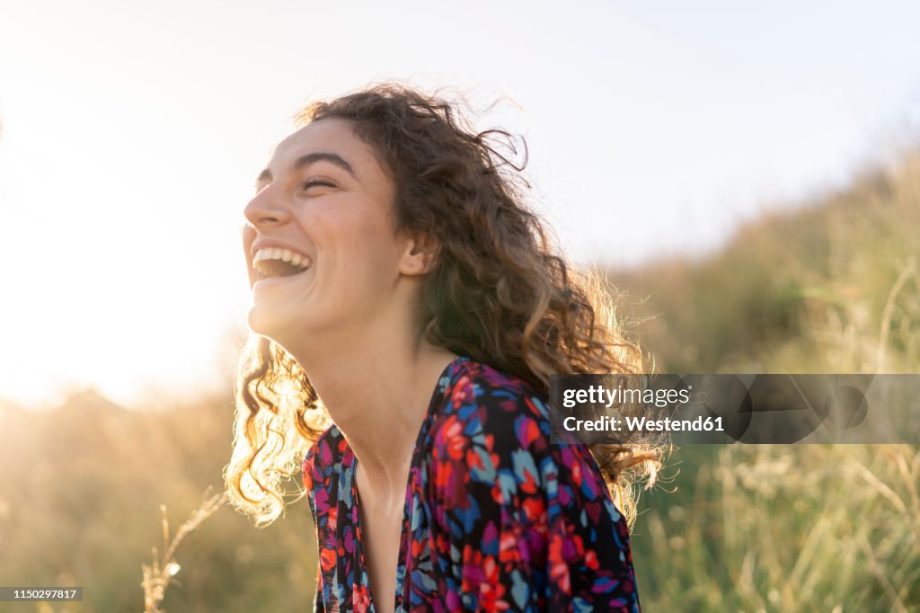 Portrait of a young woman standing in meadow, laughing