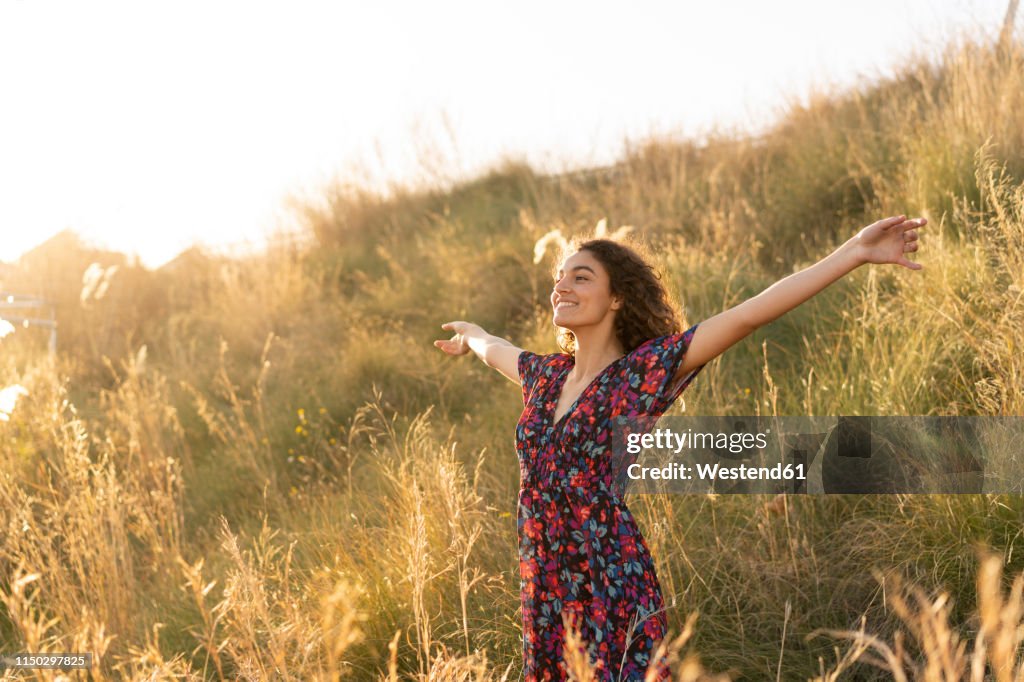 Happy young woman standing in summer meadow
