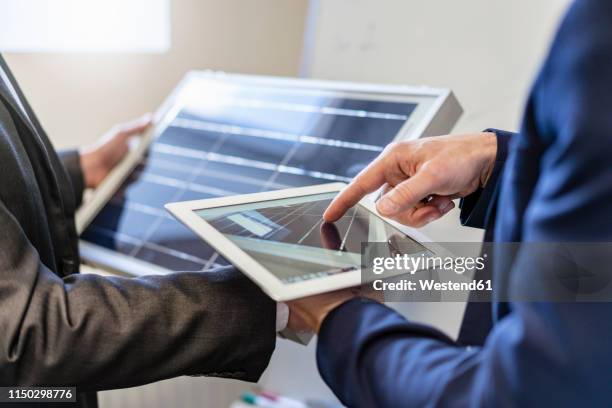 close-up of two businessmen in office with solar cell and tablet - economic discussion stock pictures, royalty-free photos & images