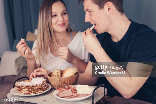 young couple having breakfast in bed - roll shirt stock pictures, royalty-free photos & images