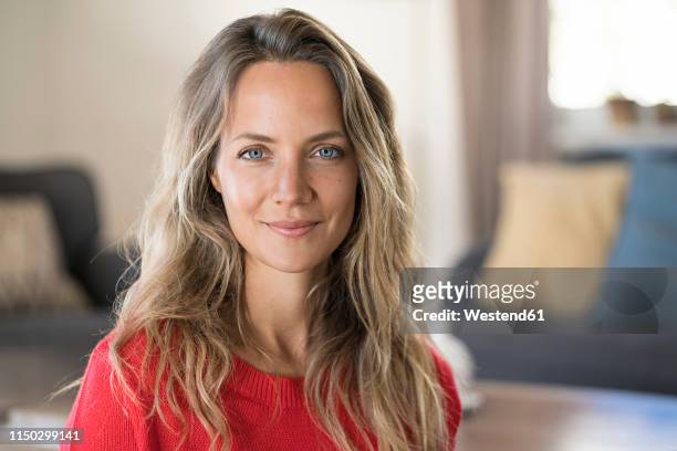portrait of smiling blond woman at home - female blonde blue eyes stock-fotos und bilder