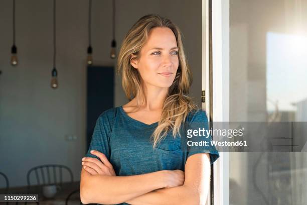 woman leaning at open window at home looking sideways - open window frame stock pictures, royalty-free photos & images