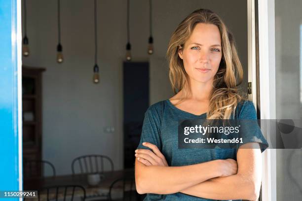 portrait of confident woman leaning at open window at home - oberteil stock-fotos und bilder