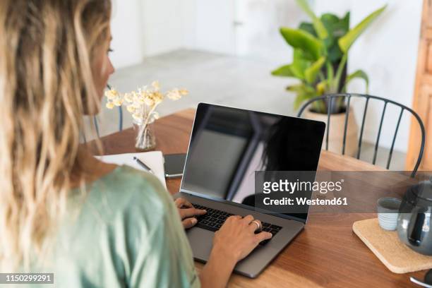 close-up of woman using laptop on wooden table at home - woman laptop screen stockfoto's en -beelden