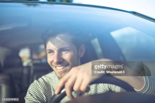 smiling young man driving car - drive car photos et images de collection