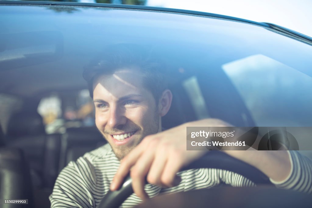Smiling young man driving car