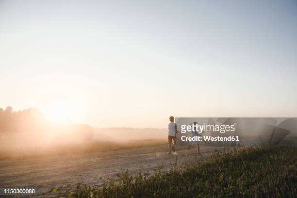 girl and boy running on a rural dirt track - stubble stockfoto's en -beelden