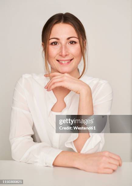 portrait of smiling young woman wearing white blouse - woman hands on chin stock pictures, royalty-free photos & images