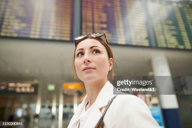 portrait of young businesswoman at the airport under arrival departure board - departure board front on fotografías e imágenes de stock