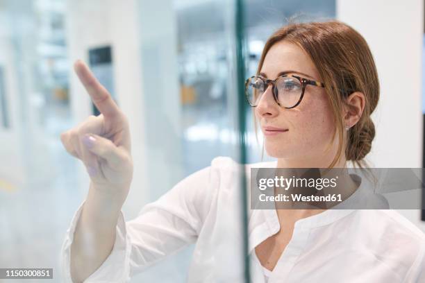 young businesswoman touching virtual touchscreen - finger touchscreen stock-fotos und bilder