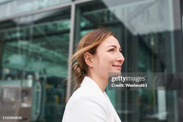 portrait of smiling young businesswoman in front of a building - business woman side stockfoto's en -beelden