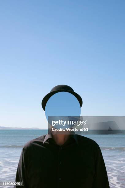 morocco, essaouira, man wearing a bowler hat with mirror in front of his face at the sea - invisible stock pictures, royalty-free photos & images