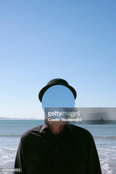 morocco, essaouira, man wearing a bowler hat with mirror in front of his face at the sea - invisível - fotografias e filmes do acervo