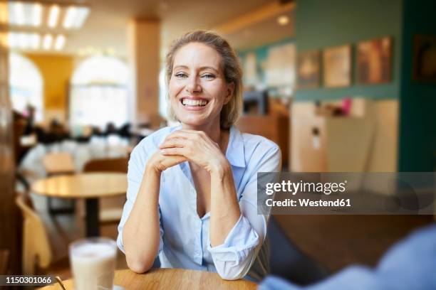 portrait of happy woman in a cafe - white blouse stock-fotos und bilder