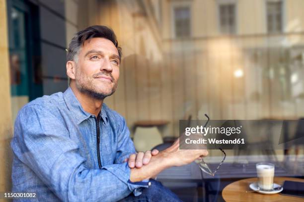 portrait of man behind windowpane in a cafe - café express stock pictures, royalty-free photos & images