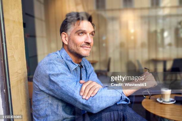 portrait of man behind windowpane in a cafe - casual business man stock-fotos und bilder
