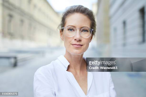 portrait of confident woman wearing glasses and white shirt in the city - selective focus stock-fotos und bilder