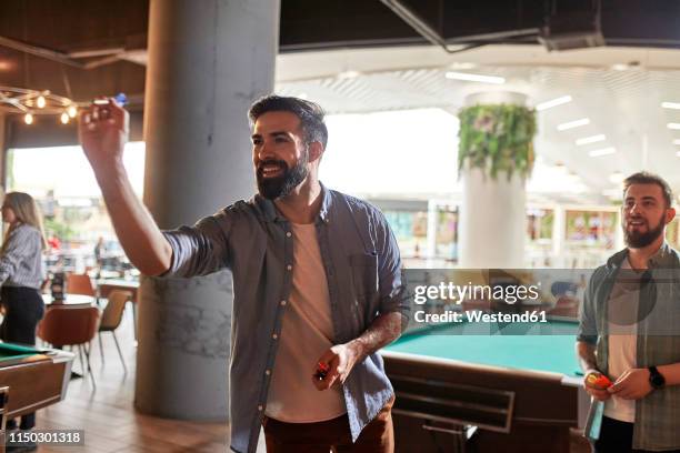 smiling man playing darts - freccette foto e immagini stock