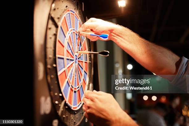 close-up of man taking out darts from electronic dartboard - darts stock pictures, royalty-free photos & images