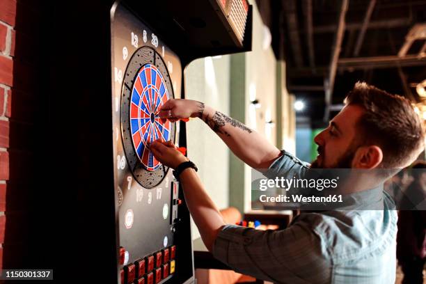 man taking out darts from electronic dartboard - darttavla bildbanksfoton och bilder