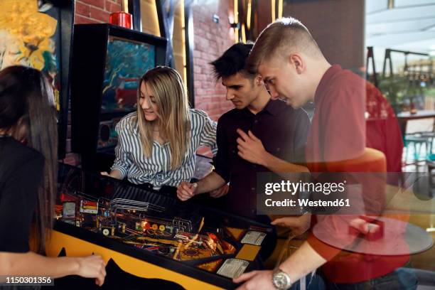 man playing pinball watched by friends - poolbiljart stockfoto's en -beelden