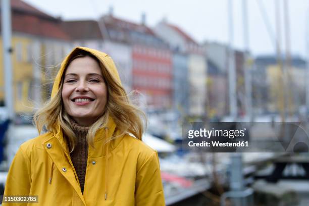 denmark, copenhagen, portrait of happy woman at city harbour in rainy weather - windy city stock pictures, royalty-free photos & images