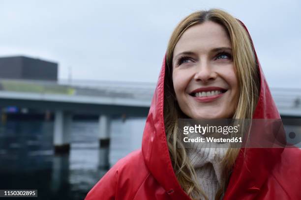 denmark, copenhagen, portrait of happy woman at the waterfront in rainy weather - headwear stockfoto's en -beelden