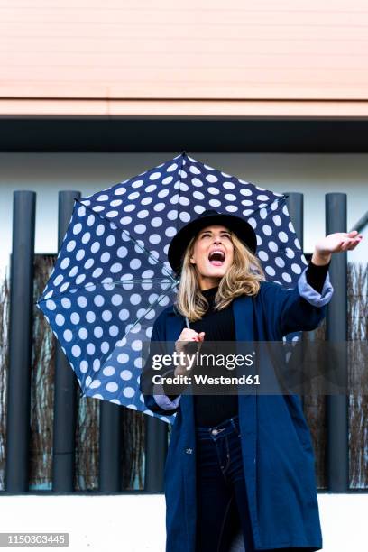 blond woman with umbrella on a rainy day - abrigo azul fotografías e imágenes de stock