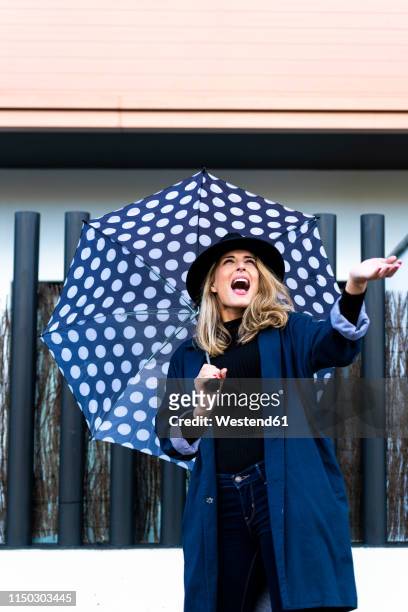 blond woman with umbrella on a rainy day - blue coat stock pictures, royalty-free photos & images