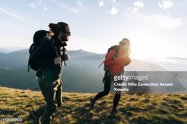 couple hiking on mountain ridge at sunrise, smiling - schweiz stock-fotos und bilder
