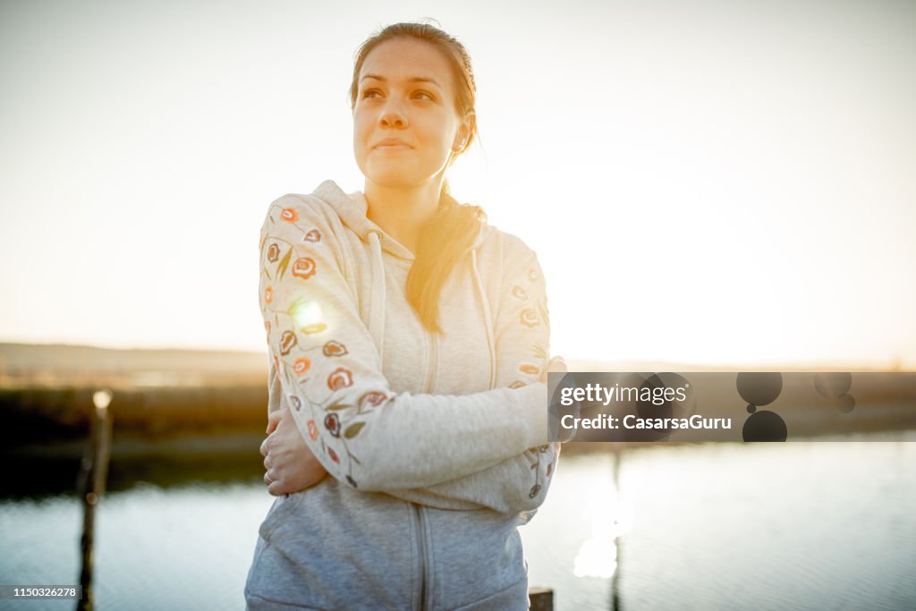 Smiling Young Woman With Arms Crossed at Sunset Outdoors
