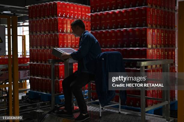 In this photo taken on April 23 an employee works at a terminal on a production line for baijiu liquor at the Luzhou Loajian bottling plant in...