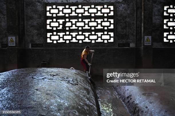 In this photo taken on April 22 a worker moistens mounds where grain is fermented at the Luzhou Laojiao distillery where baijiu is produced in...