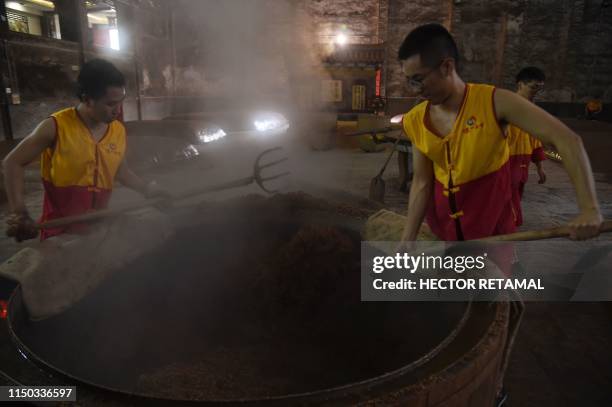 In this photo taken on April 24 workers collect fermented grain at the Luzhou Laojiao distillery where baijiu is produced in Luzhou, southwestern...