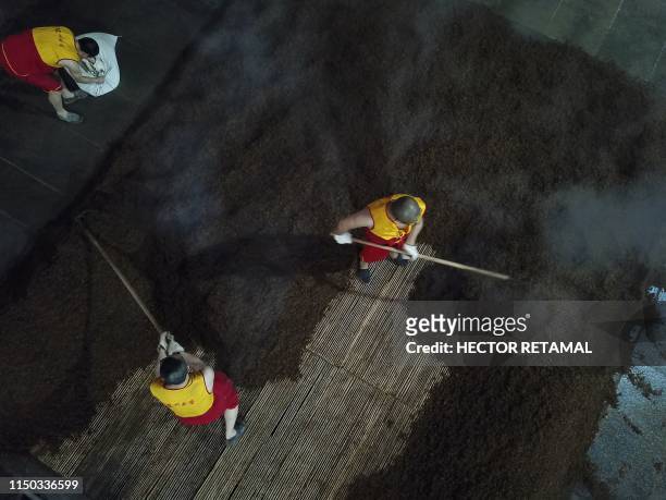 In this photo taken on April 24 workers prepare grain on a work floor at the Luzhou Laojiao distillery where baijiu is produced in Luzhou,...