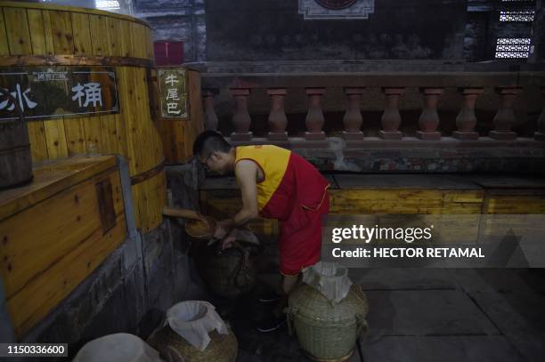 In this photo taken on April 24 a workers collects distilled baijiu liquor at the Luzhou Laojiao distillery in Luzhou, southwestern China's Sichuan...