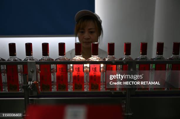 In this photo taken on April 23 an employee inspects baijiu liquor on a production line at the Luzhou Loajian bottling plant in Luzhou, southwestern...