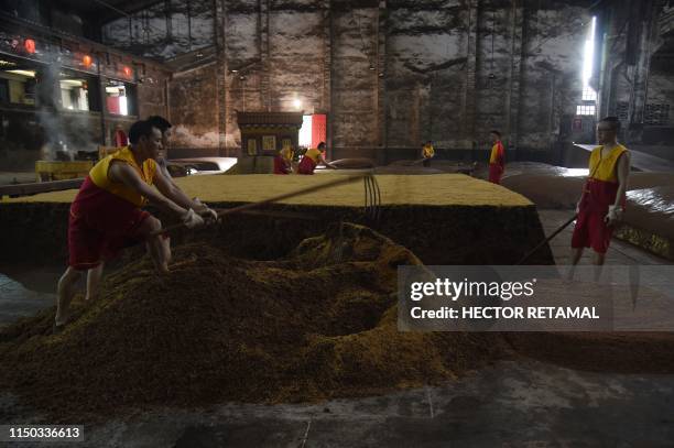 In this photo taken on April 24 workers prepare grain on a work floor at the Luzhou Laojiao distillery where baijiu is produced in Luzhou,...