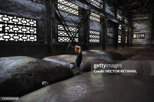 In this photo taken on April 22 a worker moistens mounds where grain is fermented at the Luzhou Laojiao distillery where baijiu is produced in...