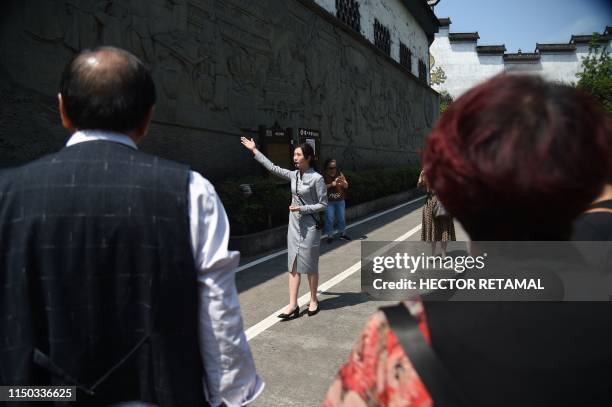 In this photo taken on April 22 visitors look on at a guide during a tour of the Luzhou Laojiao distillery where baijiu is produced in Luzhou,...