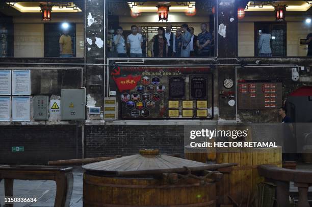 In this photo taken on April 22 visitors look on during a tour of the Luzhou Laojiao distillery where baijiu is produced in Luzhou, southwestern...