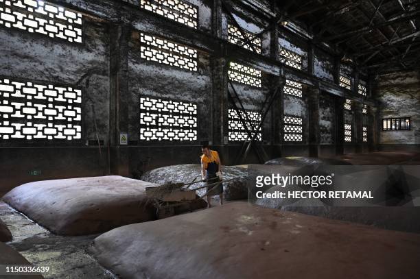 In this photo taken on April 22 a worker inspects mounds where grain is fermented at the Luzhou Laojiao distillery where baijiu is produced in...