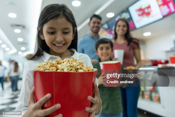 girl at the movie theater with her family eating sweet popcorn - caramel corn stock pictures, royalty-free photos & images