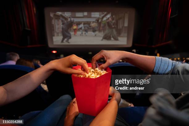 close-up on a couple at the movies eating popcorn - film industry stock pictures, royalty-free photos & images