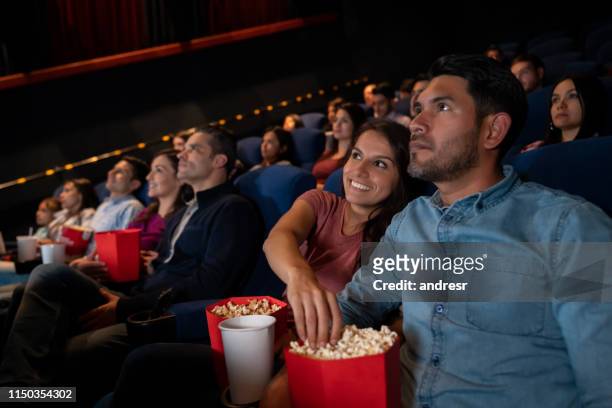 happy couple at the movies and woman stealing popcorn - large group of people eating stock pictures, royalty-free photos & images