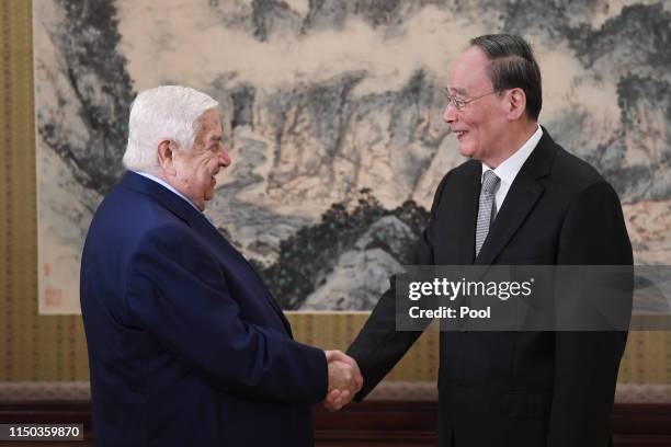 Syria's Foreign Minister Walid Al-Moualem is greeted by Chinese Vice President Wang Qishan before a meeting at the Zhongnanhai leadership compound in...